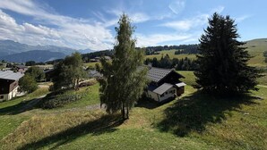 A rural landscape with houses, trees, and mountains in the background.