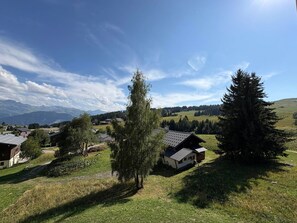 A rural landscape with houses, trees, and mountains in the background.