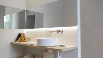 Une salle de bain moderne avec un lavabo blanc, un miroir et un porte-serviettes.