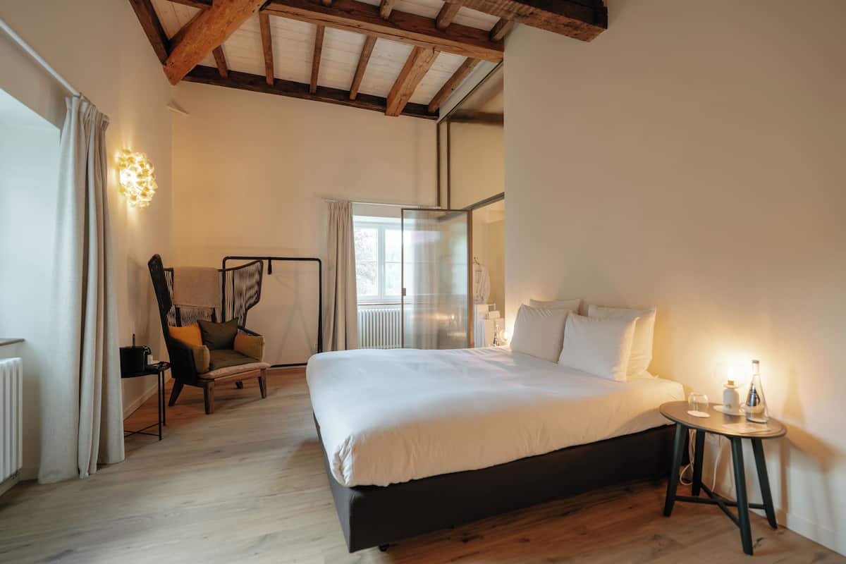 Ein Schlafzimmer mit einem Bett, einem Sessel, einem Tisch und einem Fenster.