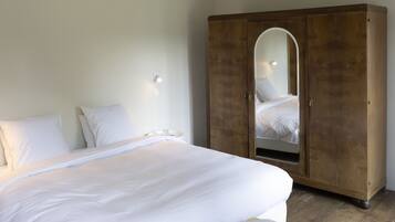 Un dormitorio con una cama grande, un armario de madera y un pequeño banco amarillo.