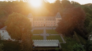 A large, symmetrical building with a central courtyard, surrounded by trees. - Château du Pont d'Oye (Habay)