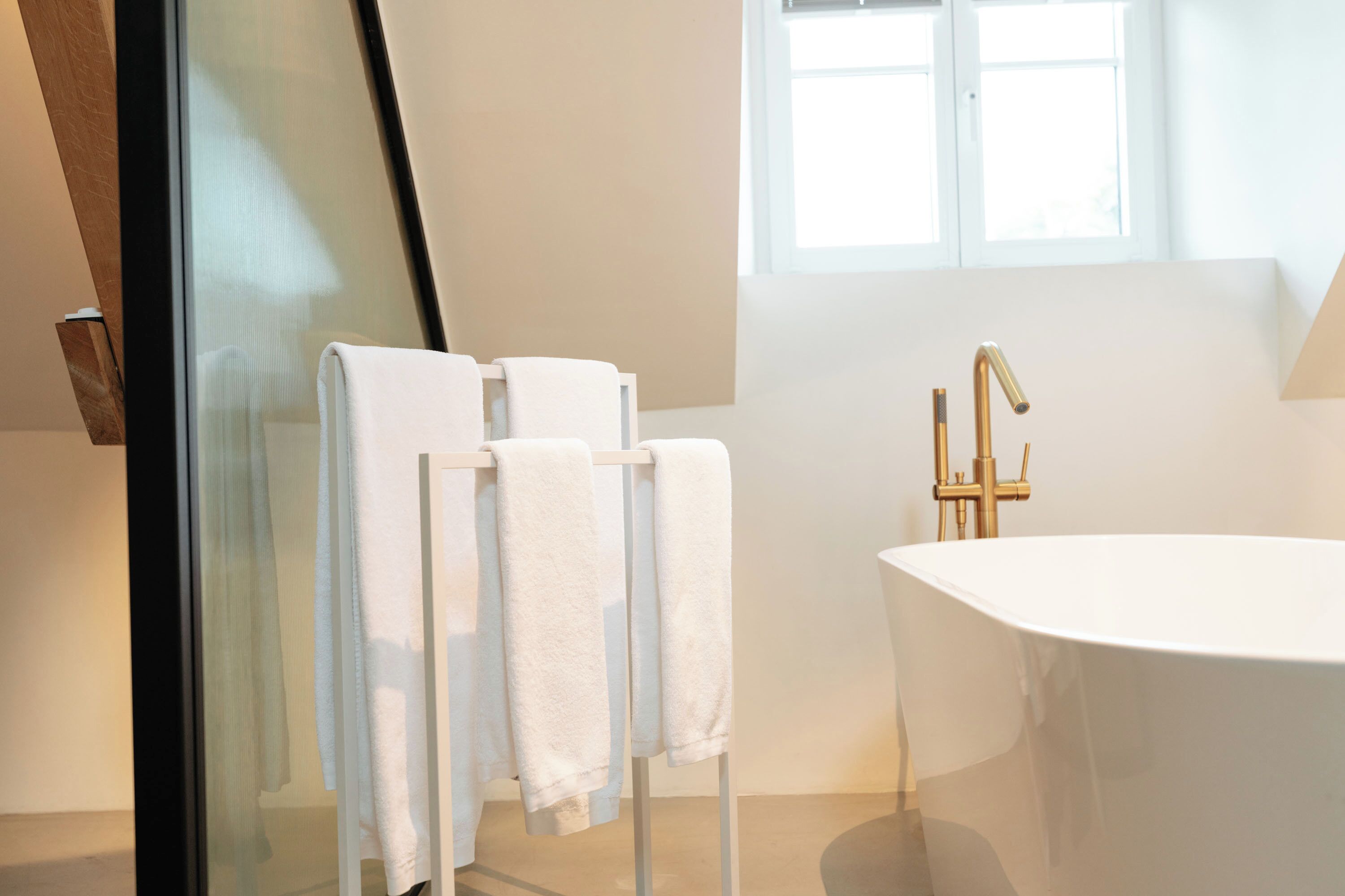 Un baño moderno con una bañera independiente, cabina de ducha con mampara de vidrio y una ventana que proporciona luz natural.