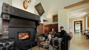 A living room with a fireplace, leather furniture, and a glass coffee table. - Château du Pont d'Oye (Habay)