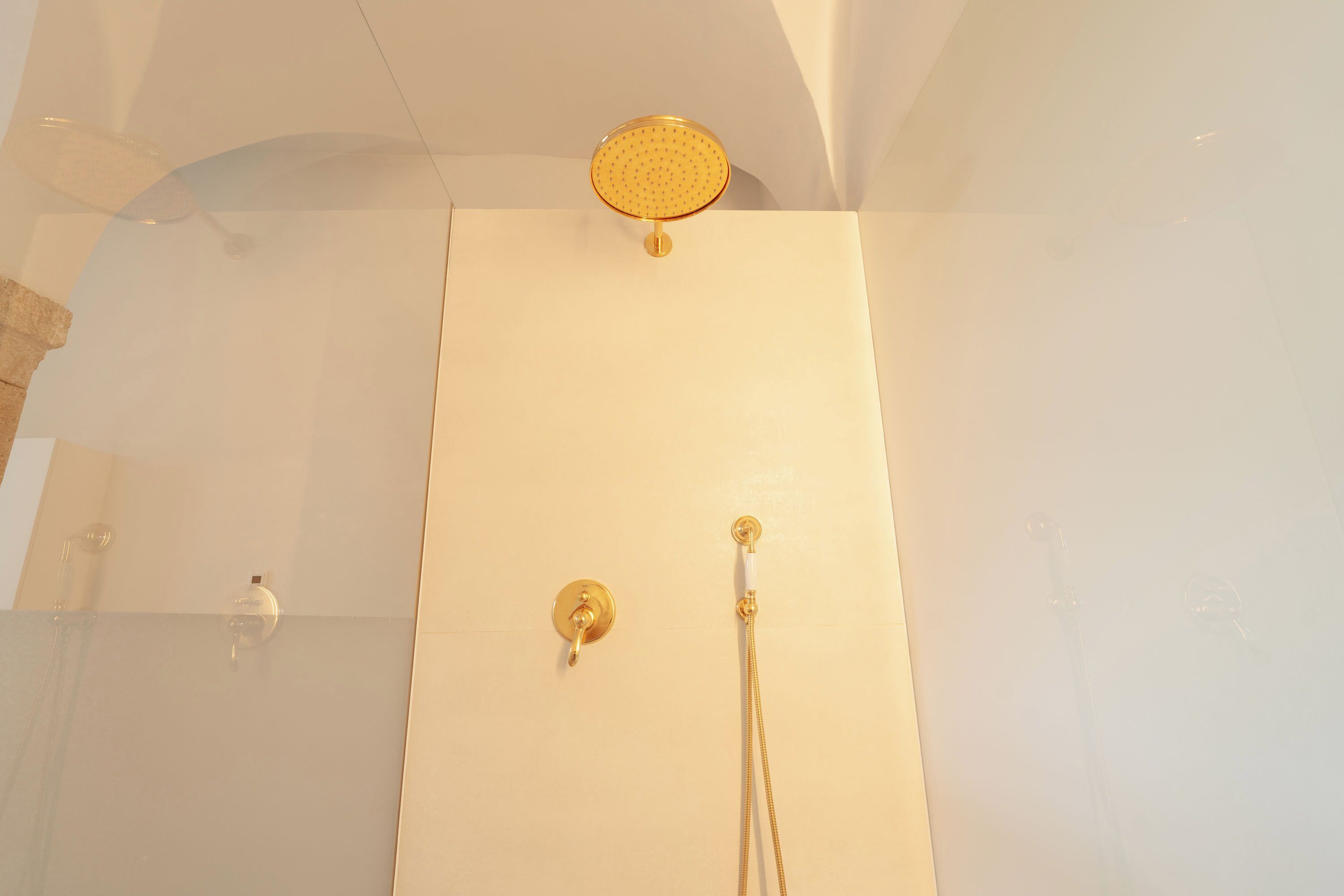 Une douche avec un pommeau de douche doré et des robinets de réglage.