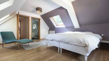 Quarto com teto inclinado, claraboia, cama, poltrona e closet espaçoso.