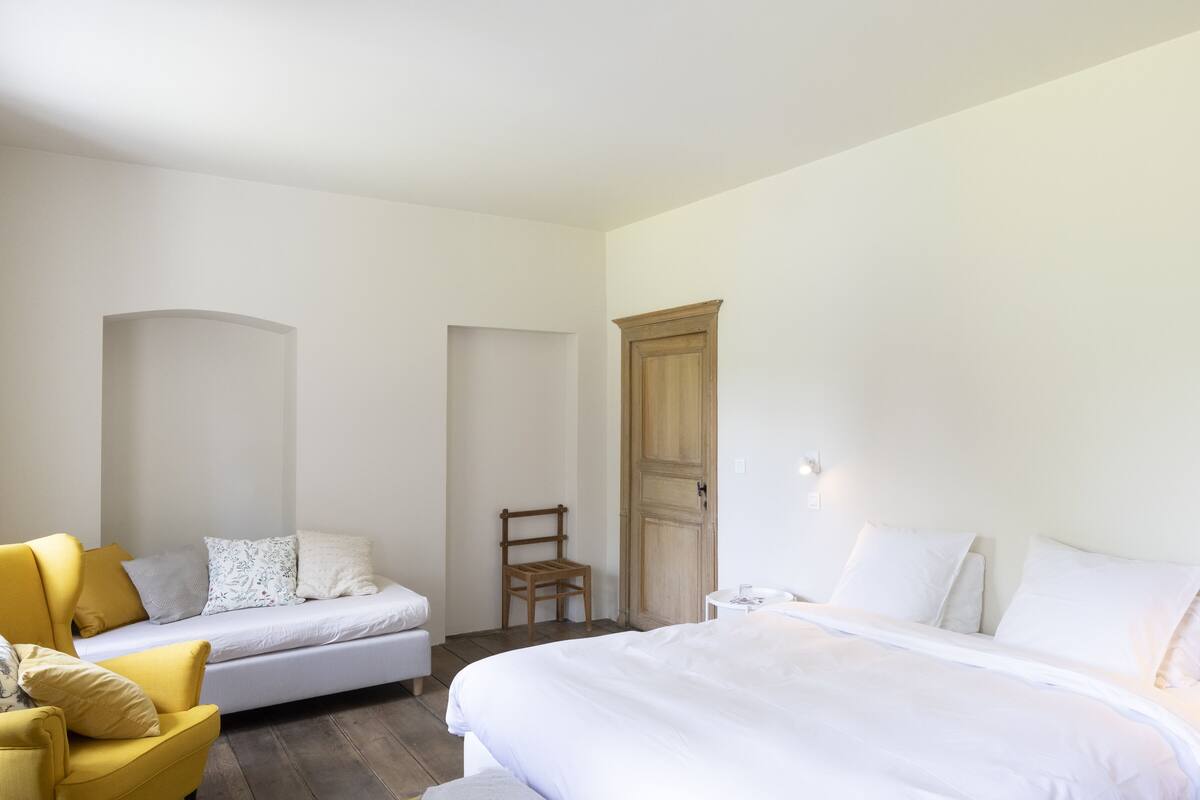 Ein Schlafzimmer mit Bett, Schlafsofa, Sessel und Kleiderschrank.