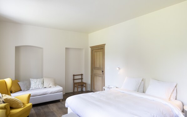 A bedroom with a bed, a sofa, a chair, and a wardrobe.