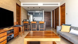 A modern living room with a wooden coffee table, a grey sofa, and a TV on a wooden stand. - Panoramic Ocean View - Hot Tub (San José del Cabo)