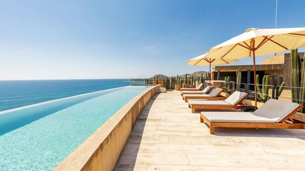 An infinity pool with lounge chairs and umbrellas overlooking the ocean. - Panoramic Ocean View - Hot Tub (San José del Cabo)
