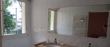 Une salle de bain avec deux lavabos, une baignoire et une fenêtre.