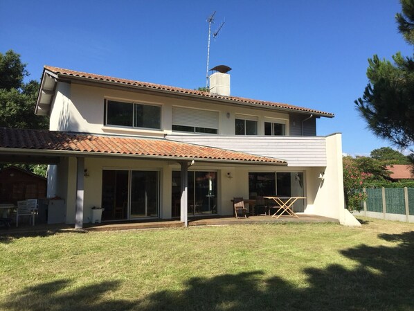 A two-story house with a tiled roof, large windows, and a covered patio area.