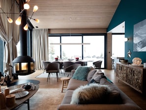 A modern living room with a large window, a dining area, and a cozy seating area with a sofa and chairs.