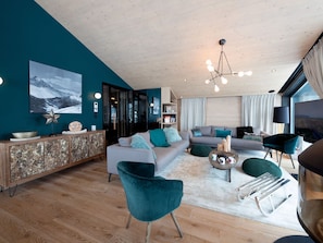A modern living room with a sofa, teal armchair, and a coffee table.