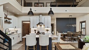 A modern kitchen with a central island, bar stools, and pendant lighting. - Private hot tub, large home, close to downtown (Red Lodge)