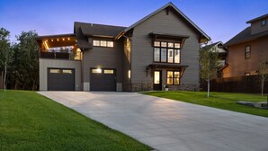 Una moderna casa a due piani con un ampio vialetto, un garage e un prato curato.