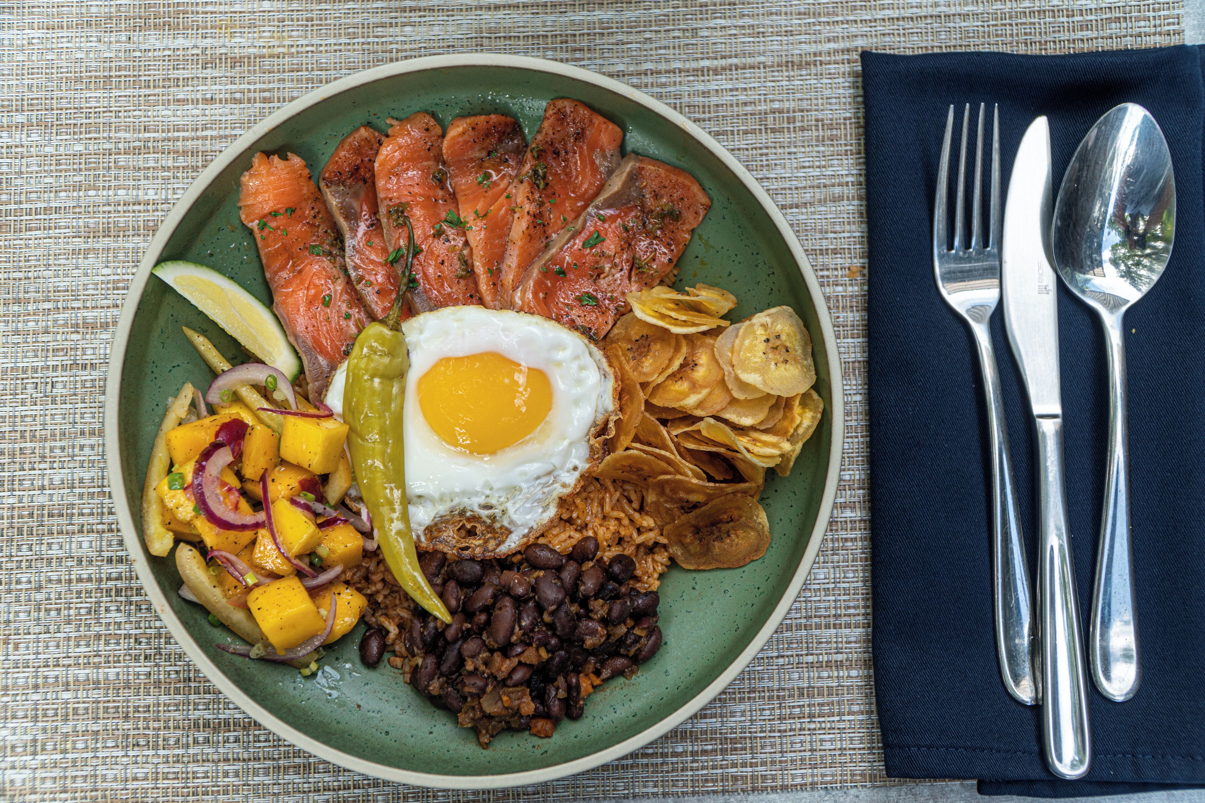 Une assiette contenant du saumon, des œufs, des haricots et des frites.