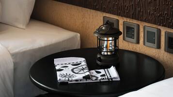 A modern hotel room with a textured wall, a black round table with a lantern, and a white sofa.