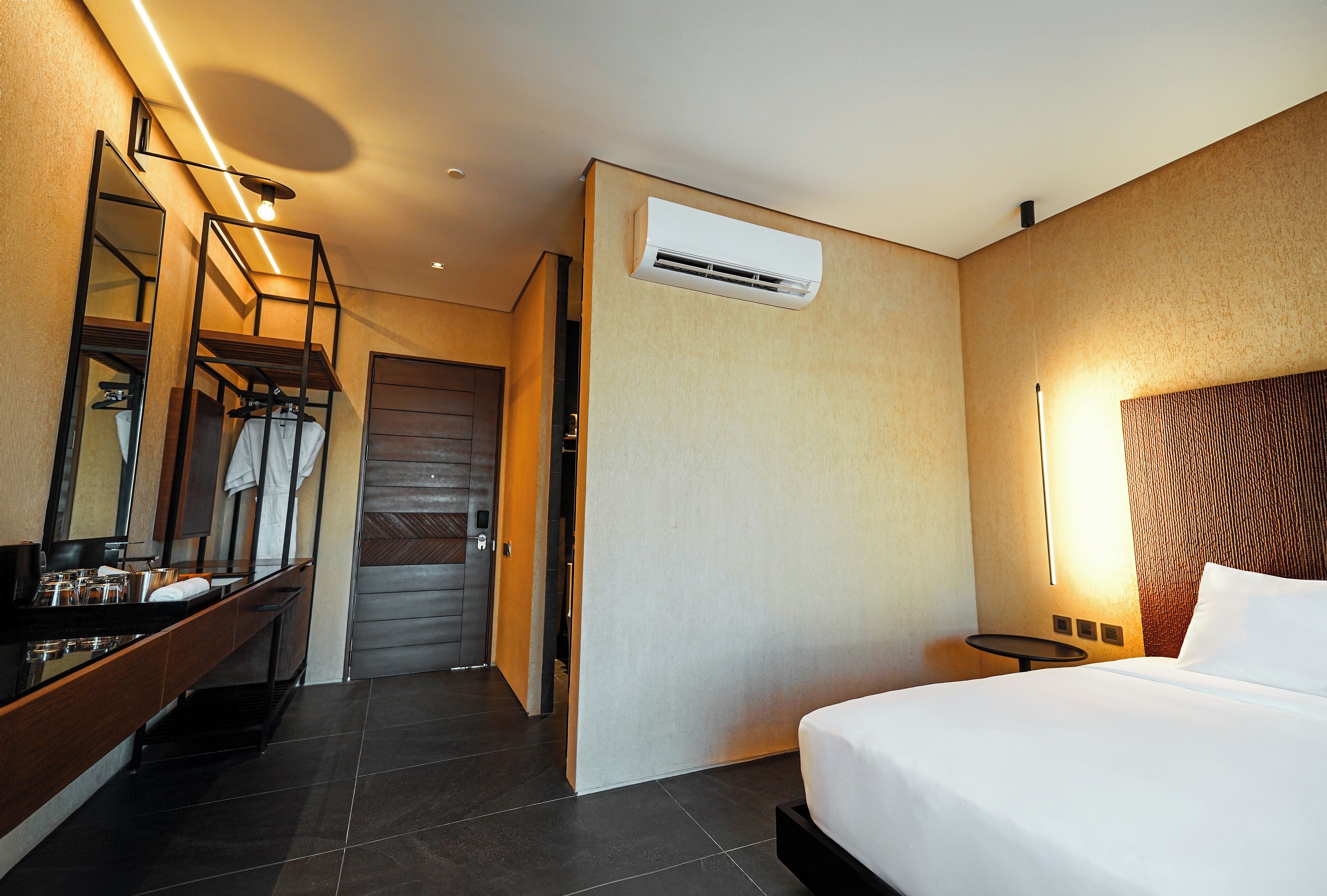Une chambre d’hôtel comprenant un lit, une salle de bain avec un miroir et un lavabo, ainsi qu’un appareil de climatisation.