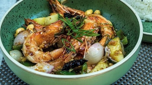 Un bol de crevettes cuites, accompagné de légumes et de riz.