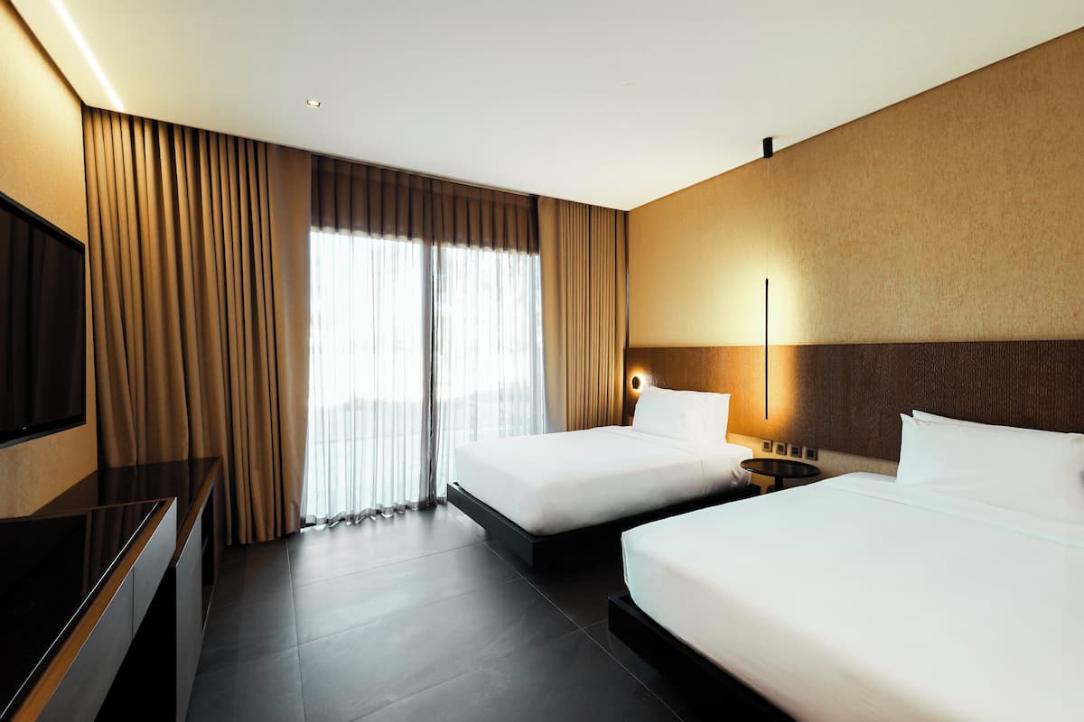 Ein Hotelzimmer mit zwei Betten, einem Fernseher und einem großen Fenster mit Vorhängen.