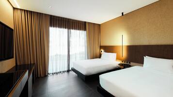 A hotel room with two beds, a TV, and a large window with curtains.