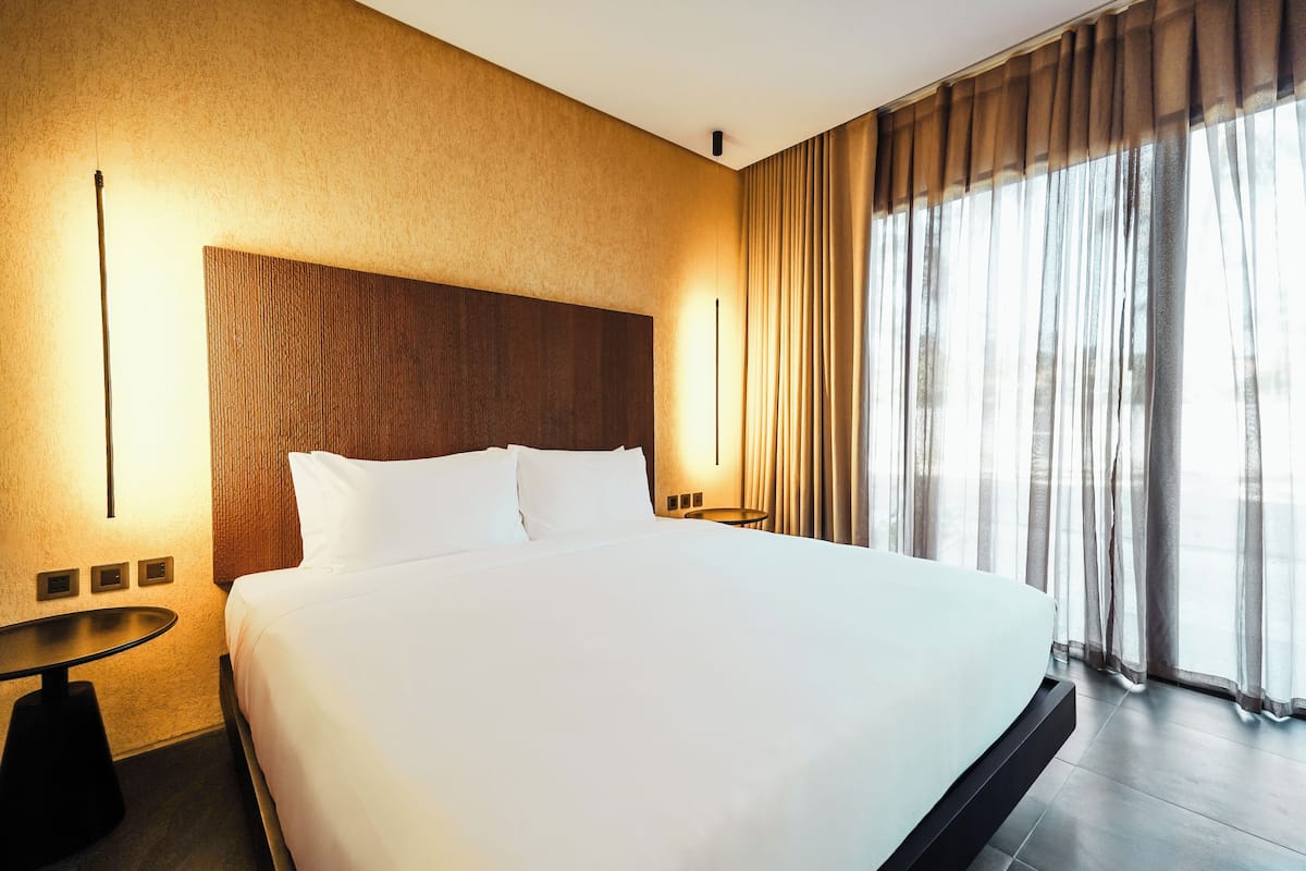Ein Hotelzimmer mit einem großen Bett, einem Nachttisch und einer Wandleuchte.