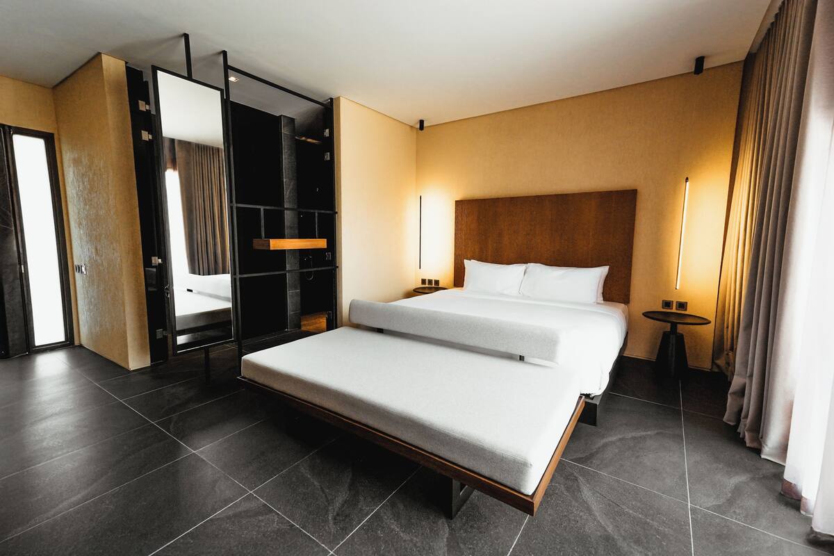 Ein modernes Hotelzimmer mit einem großen Bett, einem eingebauten Kleiderschrank und einem kleinen Tisch.