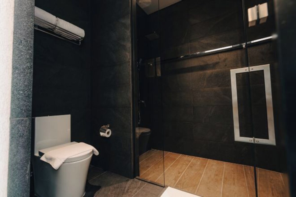 Een moderne badkamer met toilet, douche en spiegel.