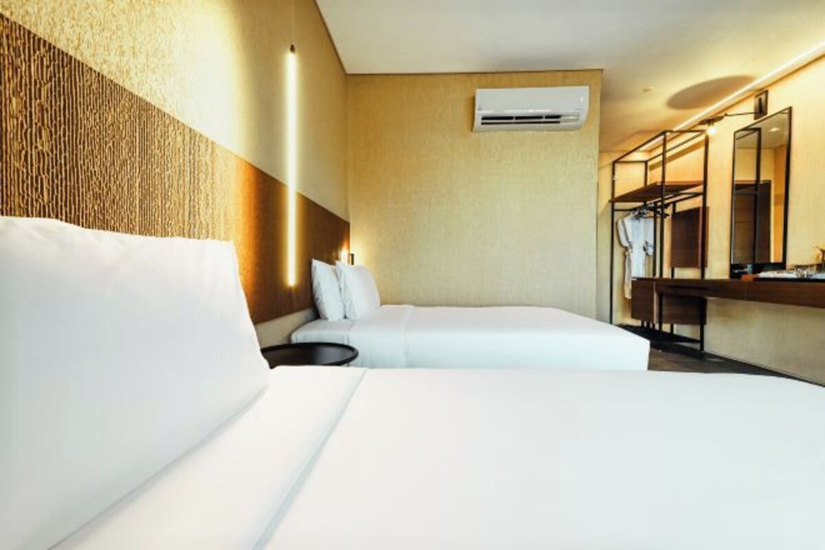 Een hotelkamer met een groot bed, nachtkastje, spiegel en een airconditioning aan de muur.