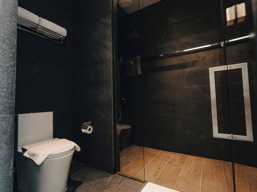 Une salle de bain moderne équipée de toilettes, d’une douche et d’un miroir.