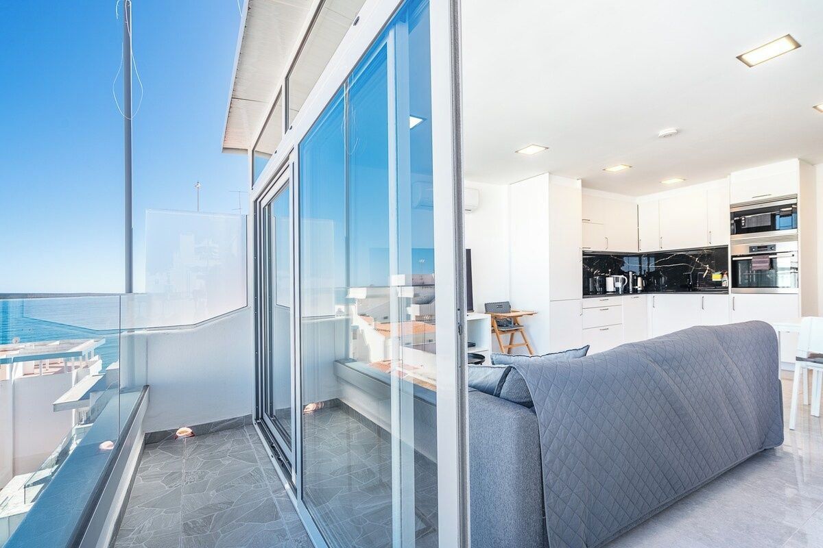 Un apartamento moderno con balcón, cocina y vista al mar.