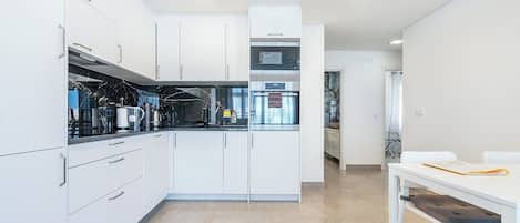A modern kitchen with white cabinets, a black countertop, and built-in appliances.