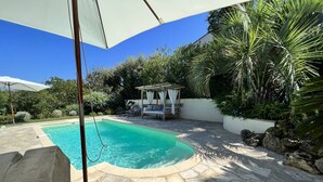 A swimming pool with stone tiles, a covered seating area, and surrounding greenery. - Luxurious Villa: 4 Bedrooms, Heated Pool, Stylish Interiors, Near Village in La Croix-Valmer (La Croix-Valmer)