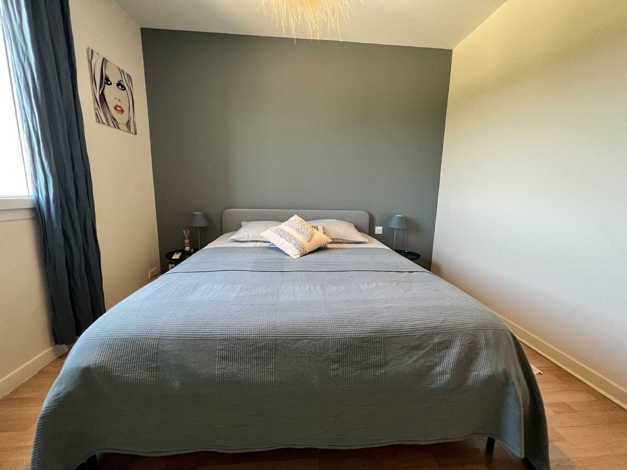Een slaapkamer met een groot bed, twee nachtkastjes, een lamp en een schilderij aan de muur.