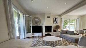 A modern living room with a fireplace, a sofa, a coffee table, and a TV. - Luxurious Villa: 4 Bedrooms, Heated Pool, Stylish Interiors, Near Village in La Croix-Valmer (La Croix-Valmer)