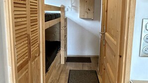 A narrow wooden hallway with bunk beds and a small cabinet.