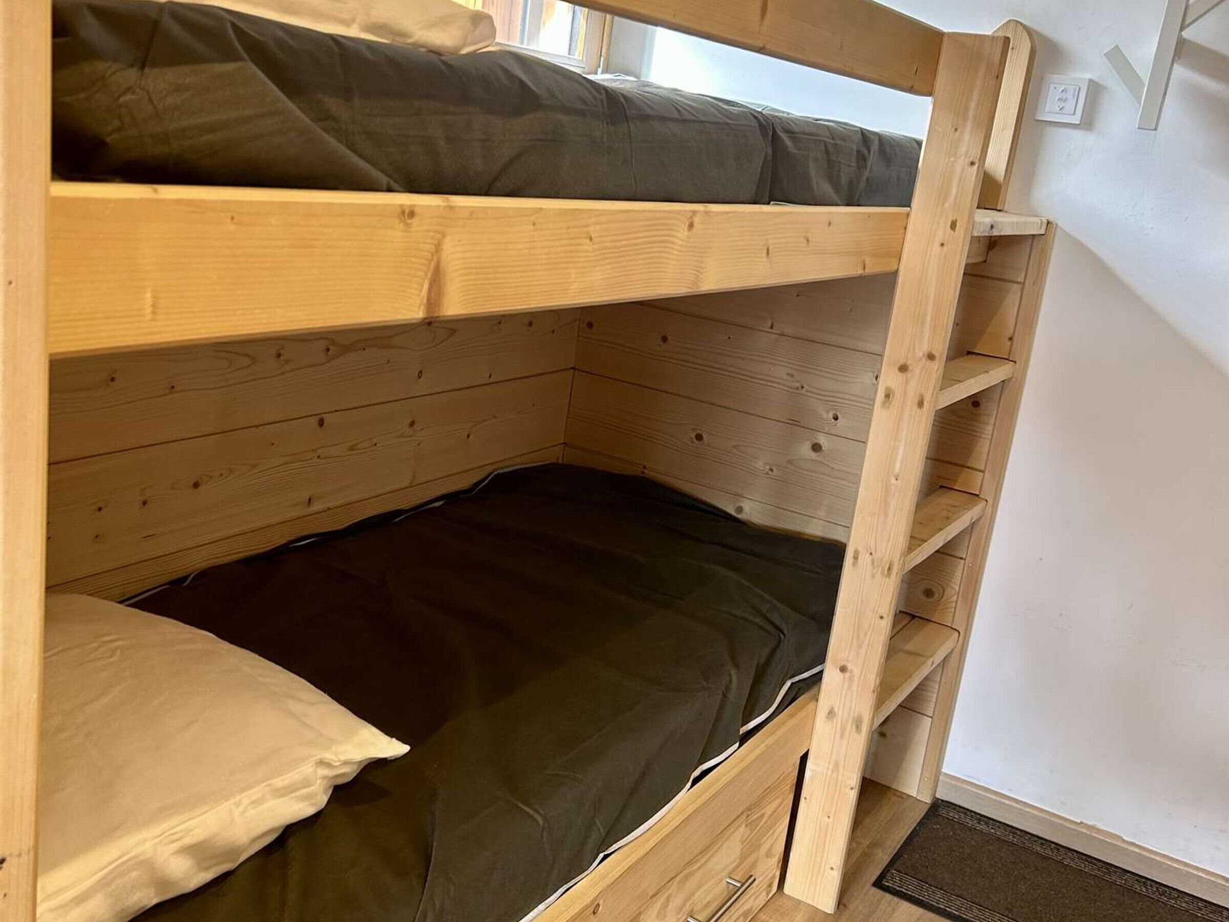 Een stapelbed met houten frame en een matras.