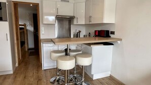 A compact kitchen with a wooden countertop, white cabinets, and a built-in washing machine.