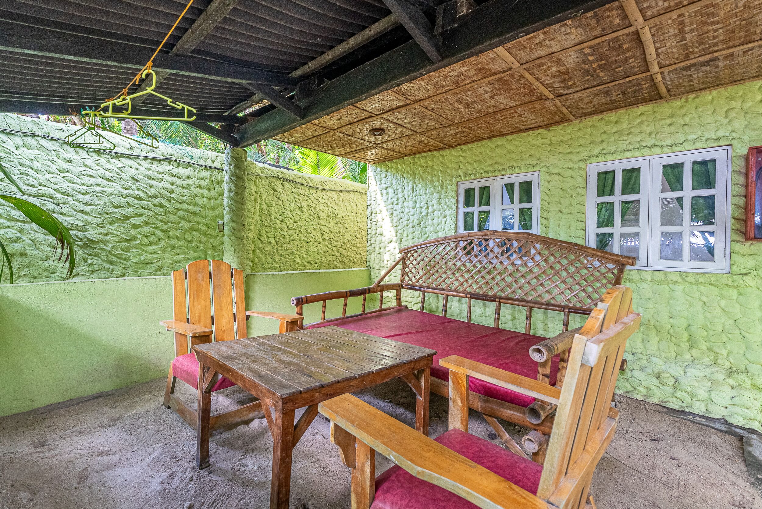 A room with a wooden table and bench, a hanging clothes rack, and a window with curtains.