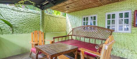 A room with a wooden table and bench, a hanging clothes rack, and a window with curtains.