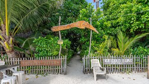A pathway leading to a beach area with signs reading "Victory Seaside Home" and "Ice Cold Buko for Sale".