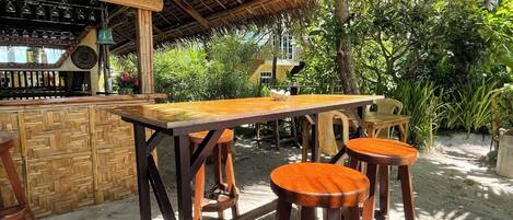 Un área de bar al aire libre con mobiliario de madera y techo de paja.