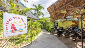 A gated entrance to Victory Seaside Home with a signboard, a concrete pathway, and parked motorcycles.