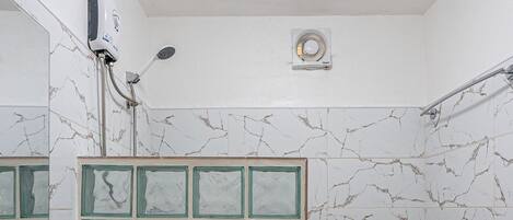 A bathroom with a white sink, a toilet, a shower with a glass door, and a ceiling light.