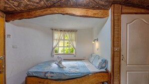 A rustic bedroom with a wooden bed, a window with curtains, and a door.