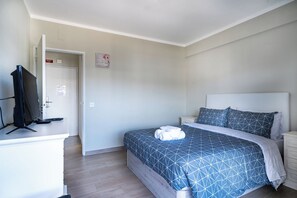 A bedroom with a bed, a desk with a computer, and a door leading to another room. - Beachfront Apartment, Sea View, Armação de Pêra (Armação)