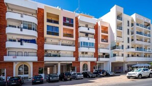 A multi-story hotel with balconies, a parking area, and a clear sky. - Beachfront Apartment 4F - Armação de Pêra, Algarve (Armação)