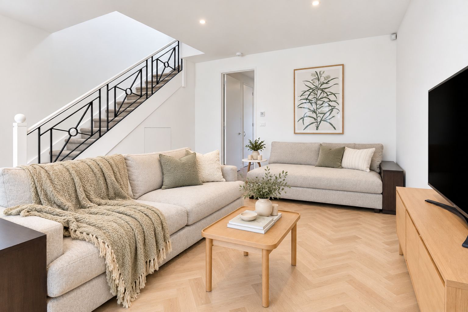 Una sala de estar moderna con una escalera, dos sofás, una mesa de centro y una televisión.