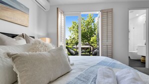 A bedroom with a bed, pillows, a window, and an open door leading to a balcony. - Bev's Retreat by Ready Set Stay - peaceful retreat and close to all attractions. (South Yarra)